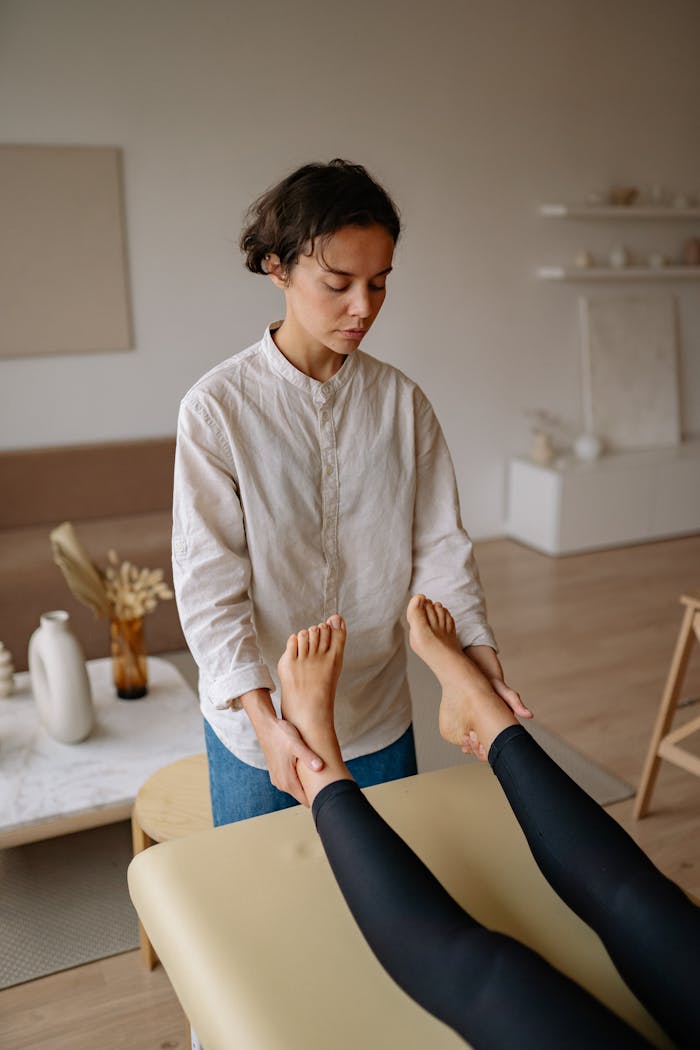 Therapist performing foot massage on woman indoors, promoting relaxation.